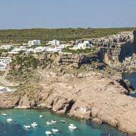 Küstenlandschaft mit Gebäuden auf Klippen und Blick auf eine Bucht mit Booten.
