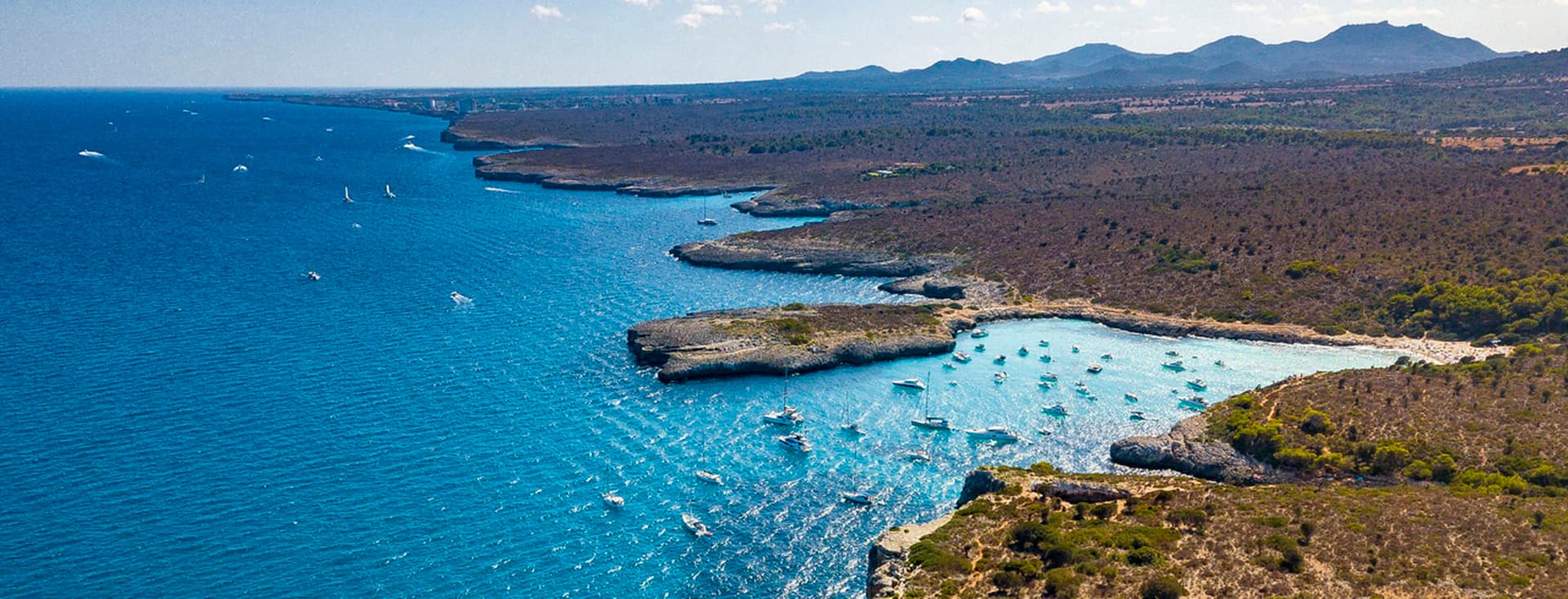 Luftaufnahme der Küstenlinie mit Booten und Bergen.