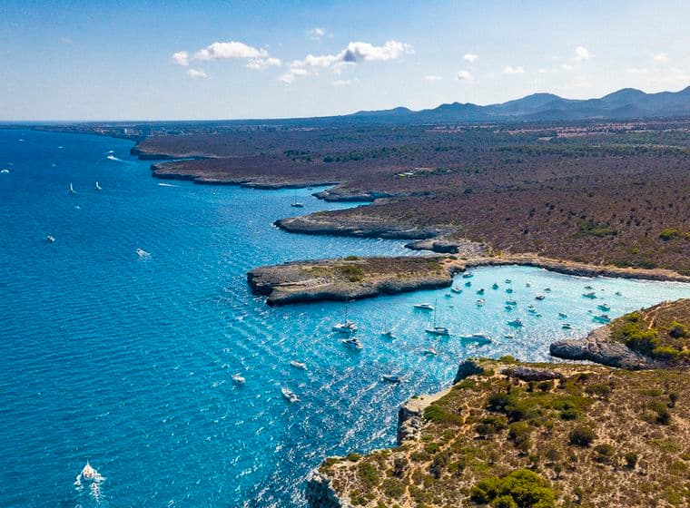Aerial view coastline with boats and mountains.