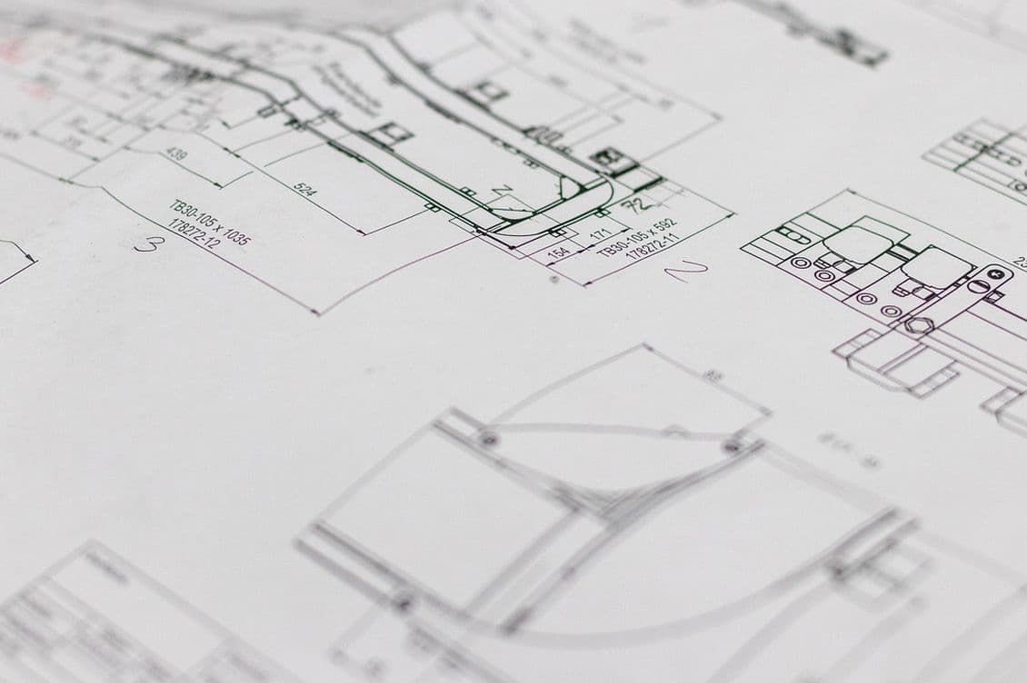 Close-up of technical engineering blueprints with detailed mechanical drawings and measurements on a white paper.