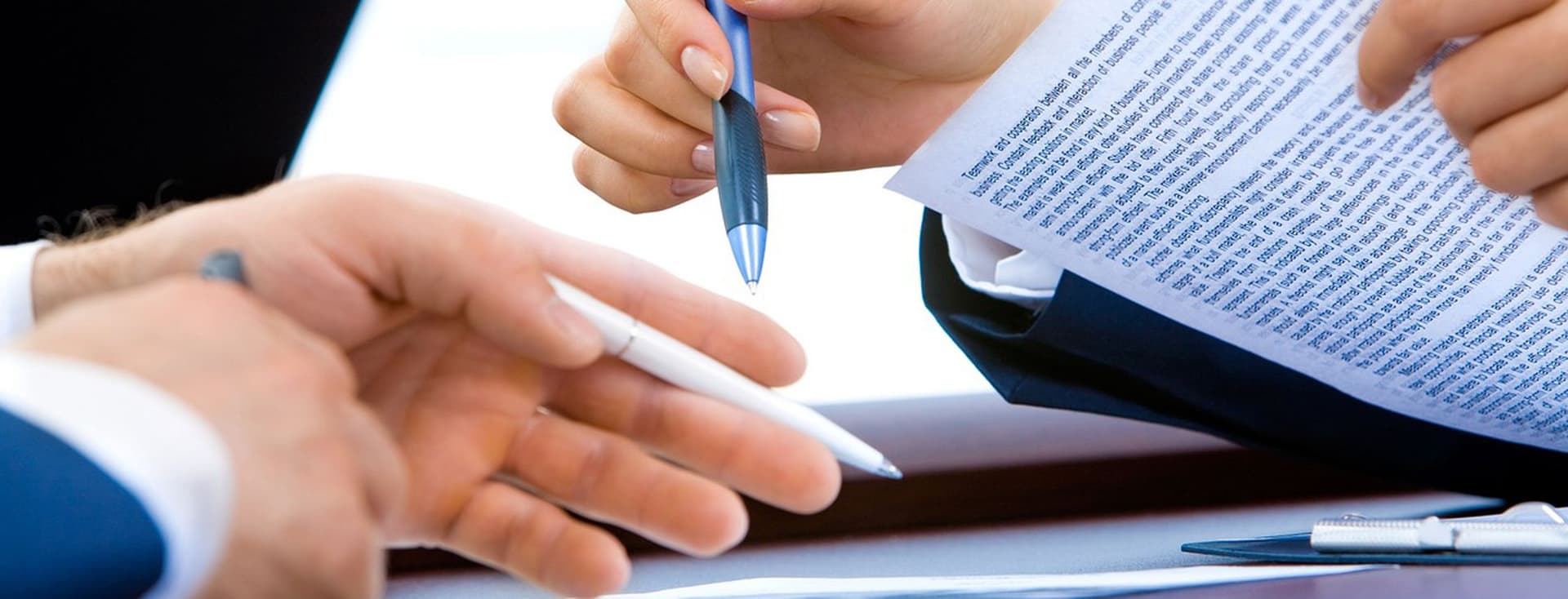 The image shows the hands of a woman and a man, gesturing as they negotiate a contract.