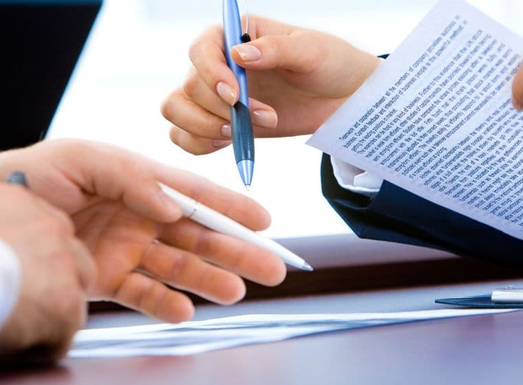 The image shows the hands of a woman and a man, gesturing as they negotiate a contract.