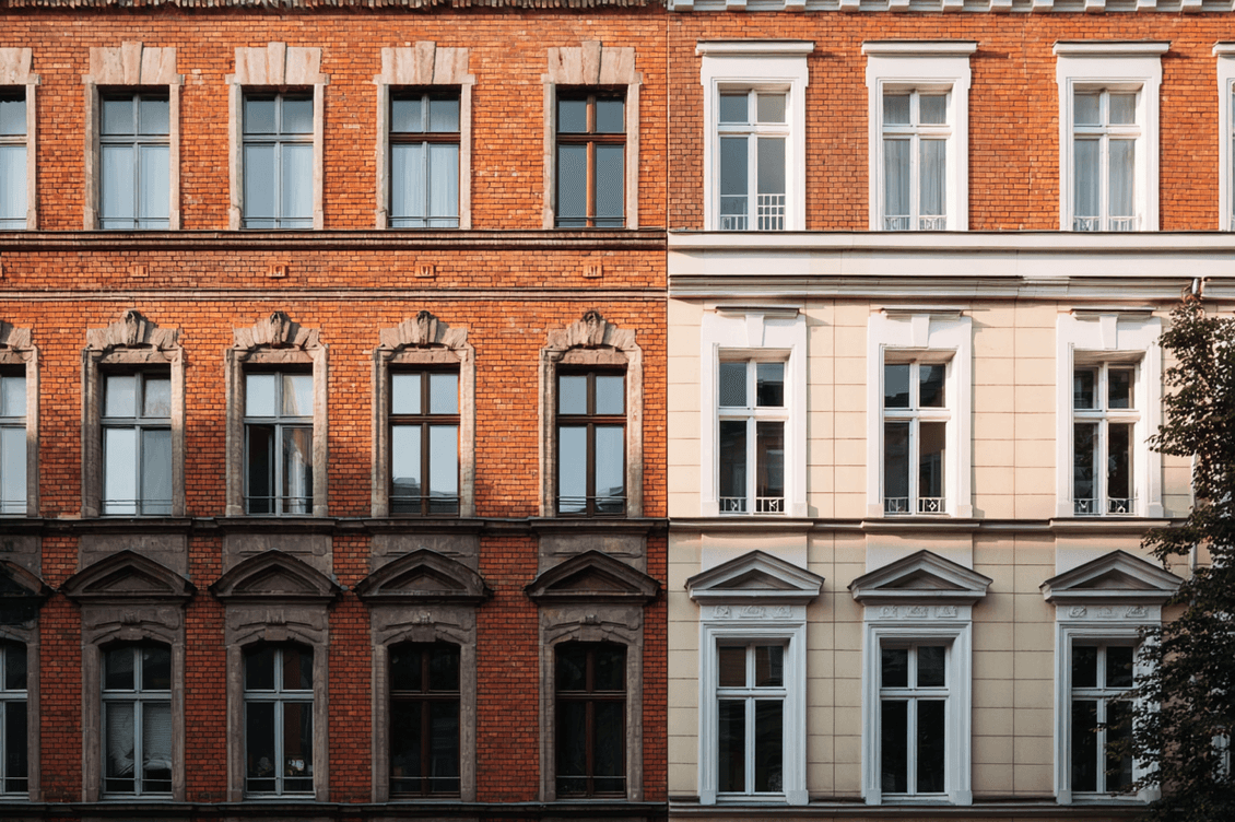 Two adjacent brick buildings with contrasting facades; red brick on the left, light beige on the right, each with symmetrical windows.