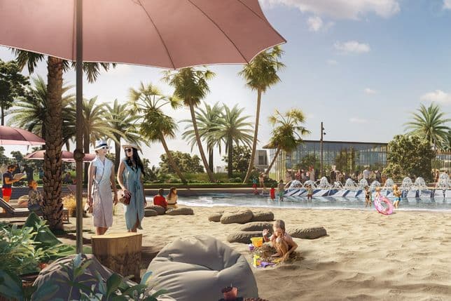 Beach scene with people relaxing under umbrellas, kids playing in the sand, and a pool with fountains. Lush palm trees and a modern building in the background.