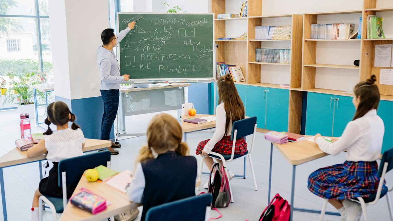 4 Alumnes a classe escoltant l'explicació del professor a la pissarra