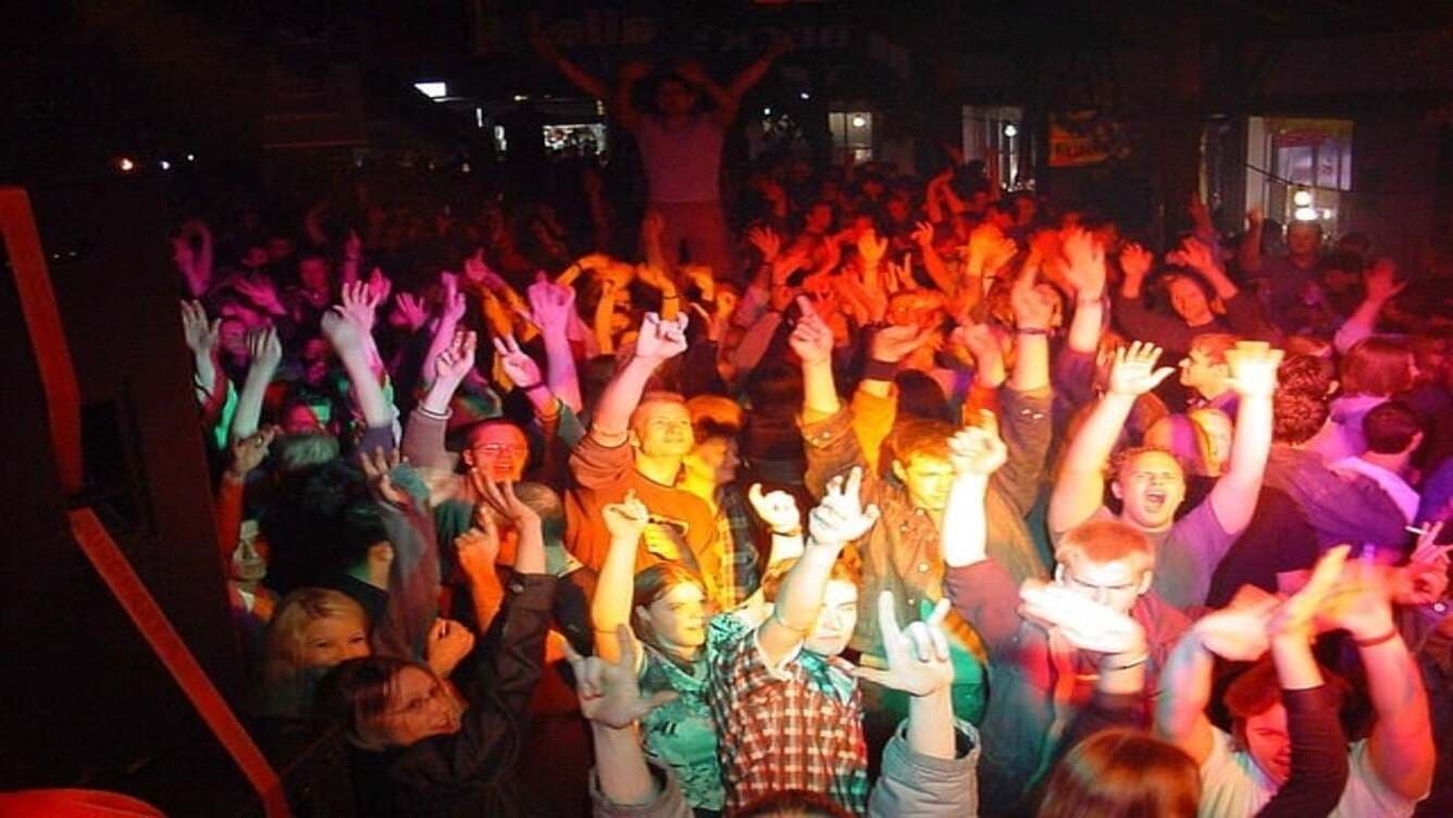 Festa divertida en un pub a Benidorm, una multitud balla amb els braços enlaire.