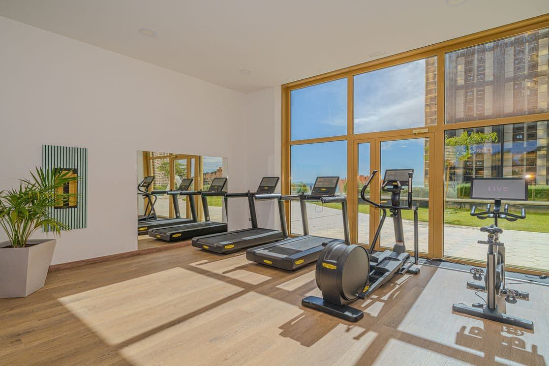 Fitnessbereich in den Gemeinschaftsräumen des Intempo-Turms. Laufmaschinen und Sportgeräte mit Blick auf den zweiten Teil des Intempo-Turms.