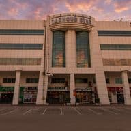 Facade of Garhoud Star building with shops on the ground floor, featuring large columns and glass windows, under a sunset sky.