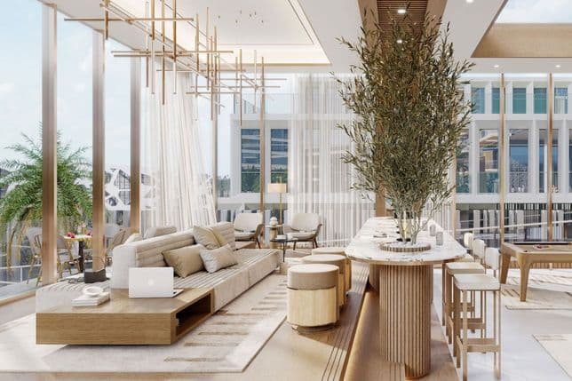 Zeitgemäßer Gemeinschaftsbereich mit bequemen Sitzgelegenheiten, Bartischen und Zimmerpflanzen unter großen Fenstern.