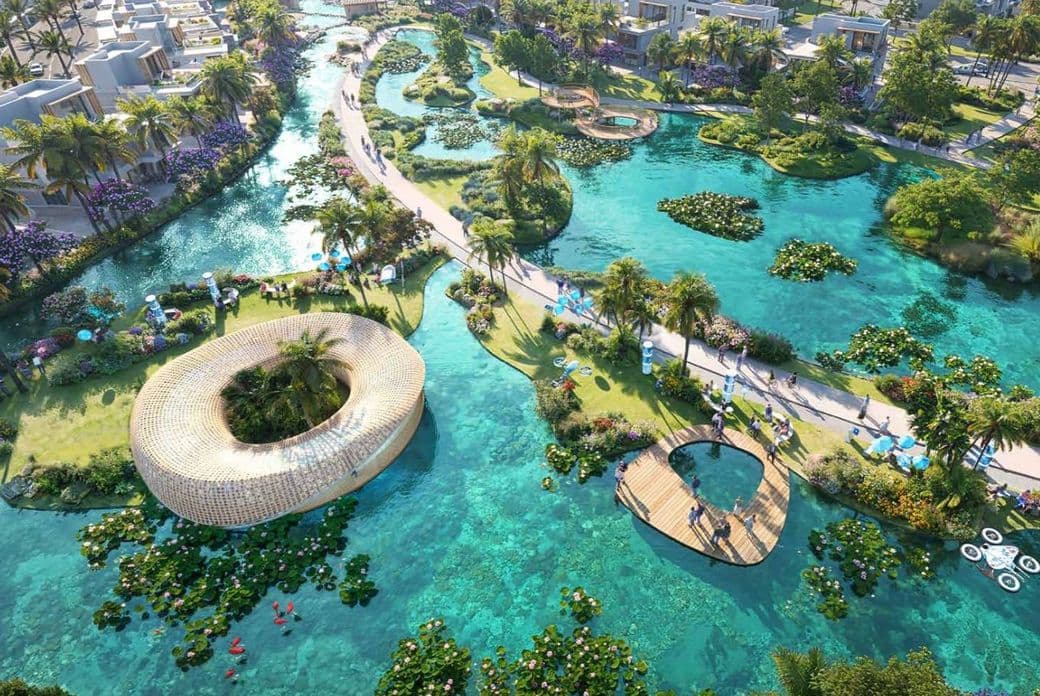 Aerial view of a tropical resort with winding waterways, lush greenery, palm trees, vibrant flowers, and unique contemporary architecture.