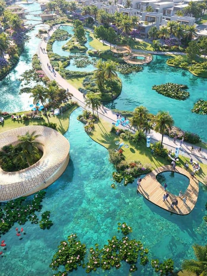 Aerial view of a tropical resort with winding waterways, lush greenery, palm trees, vibrant flowers, and unique contemporary architecture.