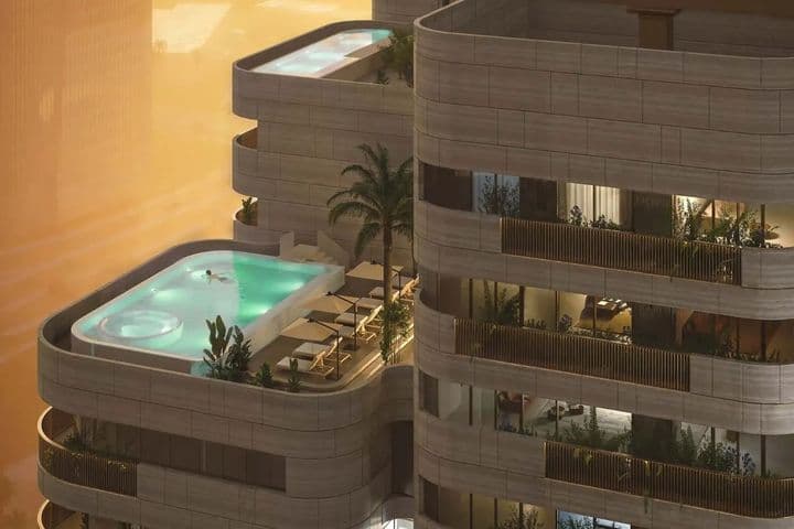 A modern high-rise building with balconies, featuring luxurious penthouses, private pools, palm trees, and lounge chairs against a sunset backdrop.