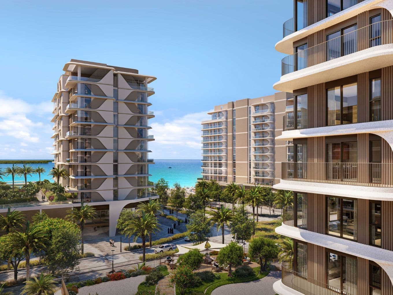 Elevated view between mid-rise towers revealing lush landscaping, a tree-lined promenade, and direct access to the turquoise beach and calm sea beyond.