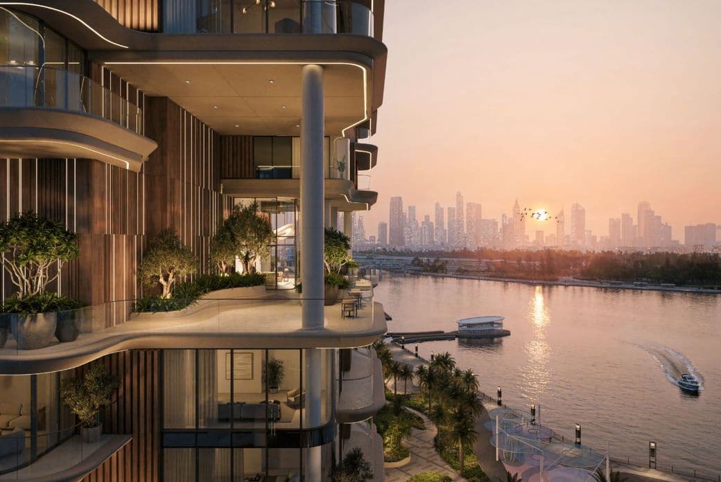 Luxuriöses Apartment am Wasser mit großzügigen Balkonen und Blick auf einen Fluss bei Sonnenuntergang, mit einer entfernten Stadtsilhouette im Hintergrund.