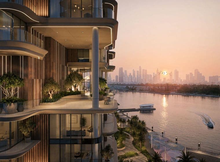 Luxuriöses Apartment am Wasser mit großzügigen Balkonen und Blick auf einen Fluss bei Sonnenuntergang, mit einer entfernten Stadtsilhouette im Hintergrund.