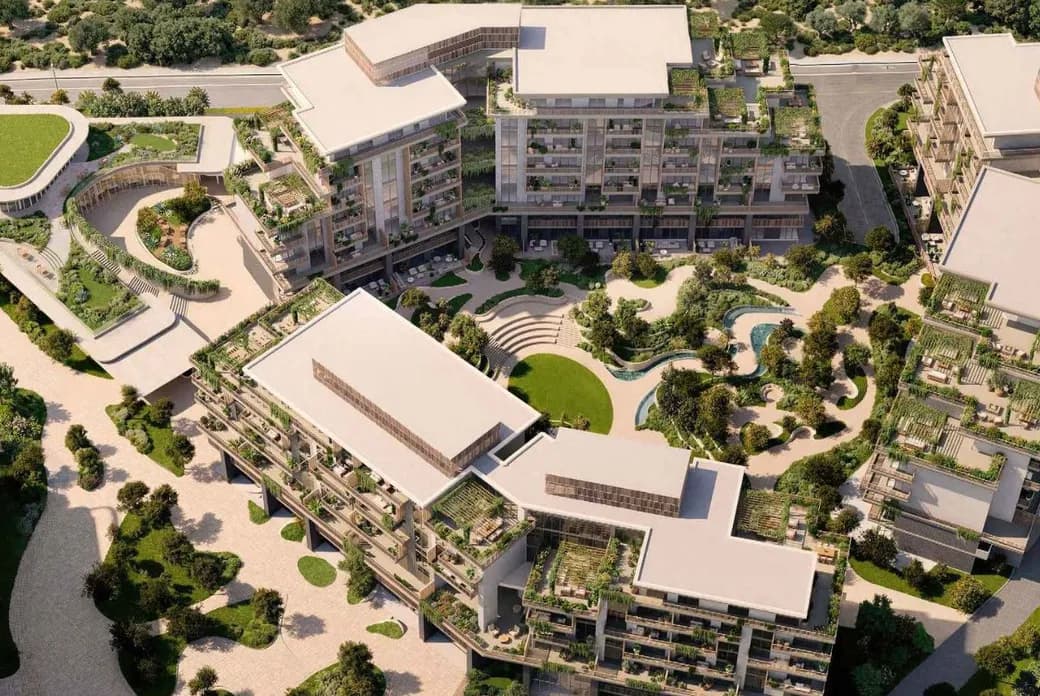 Aerial view of a modern apartment complex with green rooftop terraces, landscaped courtyard, winding pond and pathways.