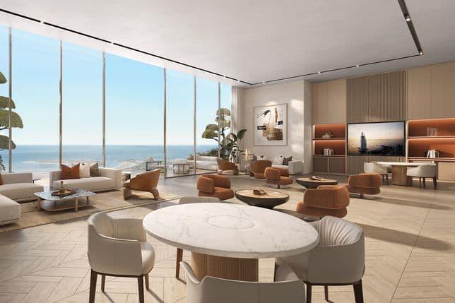 Open-plan lounge with floor-to-ceiling ocean-view windows, neutral seating, orange accent chairs, round marble table, and built-in shelving with a wall TV.