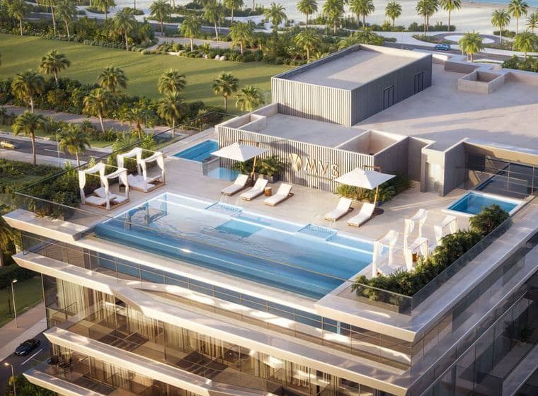 Rooftop infinity pool with lounge chairs, cabanas, and greenery, overlooking a lush landscape and palm trees.