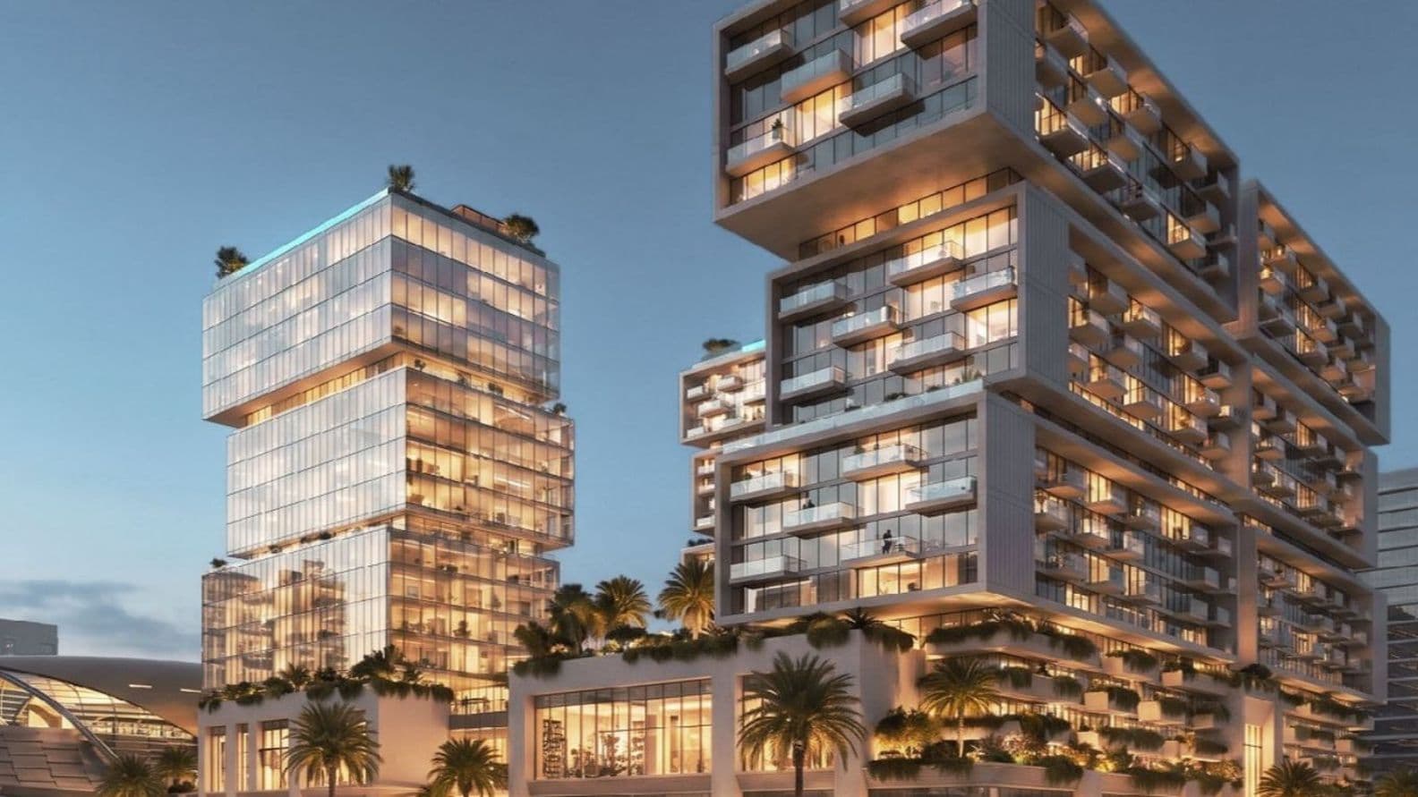 Modern, illuminated building complex with stacked glass structures, surrounded by palm trees at dusk, with people and cars in the foreground.