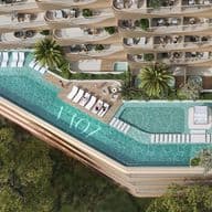 Aerial view of a luxurious building with a rooftop pool, sun loungers, and lush greenery, surrounded by curved balconies with outdoor seating.
