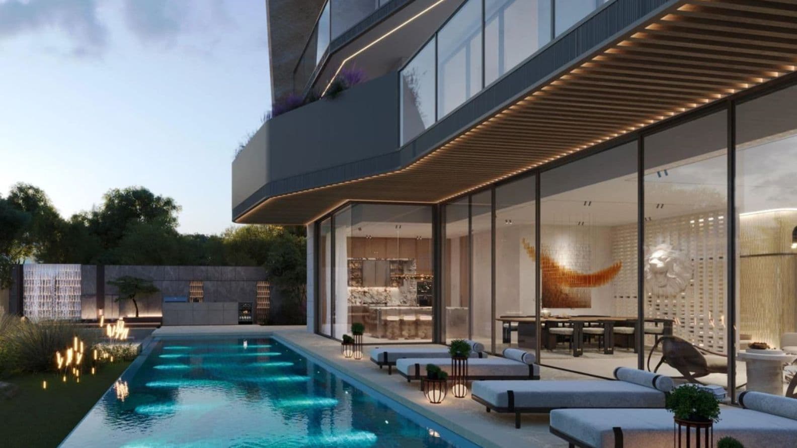 Modern villa with large glass windows, a sleek pool, and outdoor lounge chairs at dusk. Warm lighting enhances the luxurious ambiance.