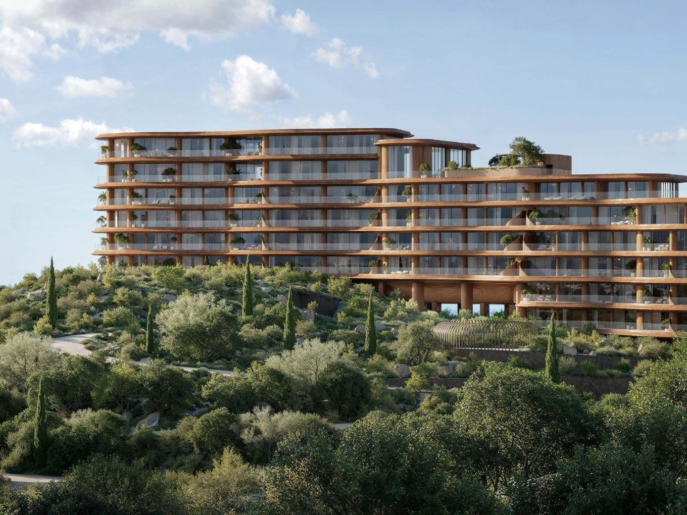 Curved architectural building surrounded by greenery with sea views in the background.