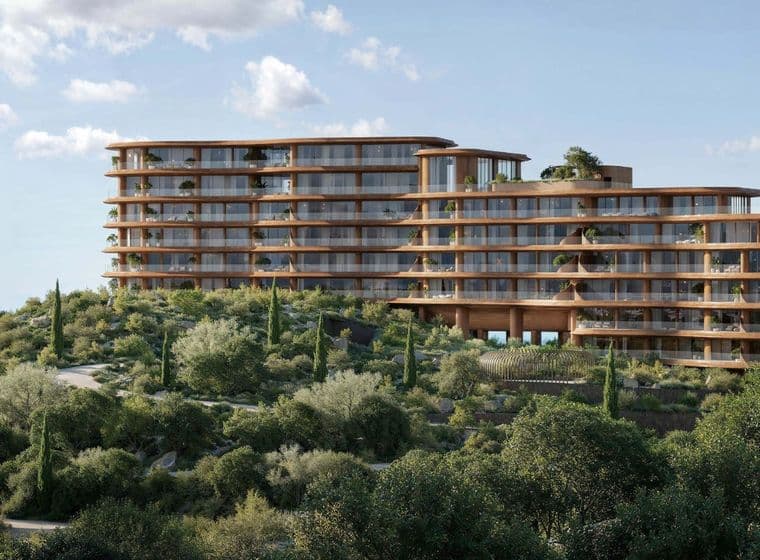 Curved architectural building surrounded by greenery with sea views in the background.
