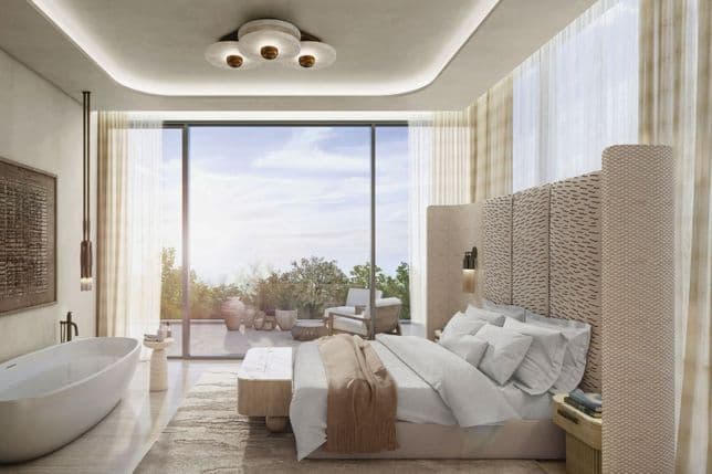 Modern bedroom with a large bed, woven headboard, indoor bathtub, and floor-to-ceiling windows revealing a sunlit view outside.