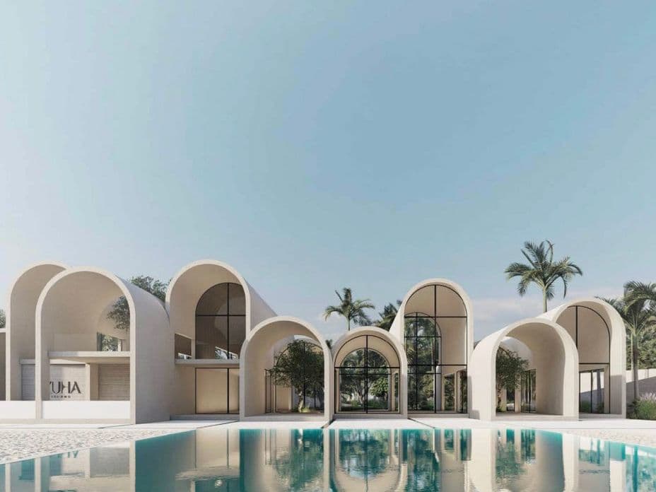 Modern building with arched roofs and large windows, reflected in a tranquil pool, surrounded by palm trees under a clear blue sky.