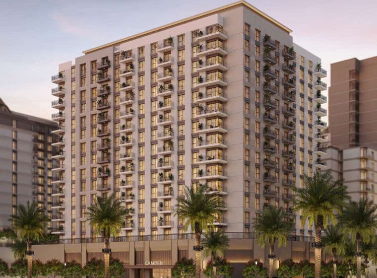 Daytime exterior of Camden residential building at Town Square, with sleek architecture, palm trees, and landscaped surroundings bathed in warm sunset light.