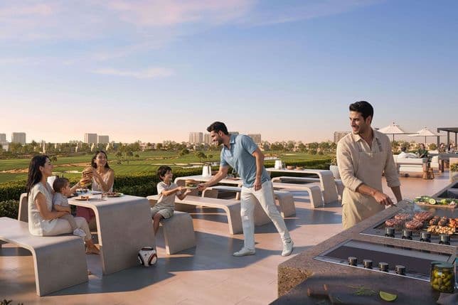 Family enjoying rooftop barbecue by a golf course at sunset — man handing a burger to a boy while another grills and others sit