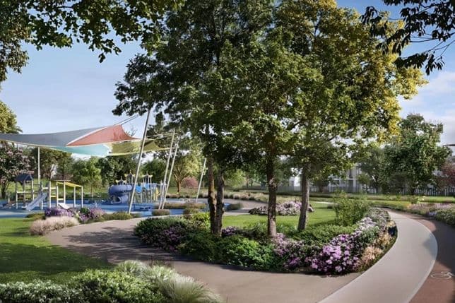 A scenic park with a playground, lush green trees, colorful flower beds, and a winding path under a blue sky.