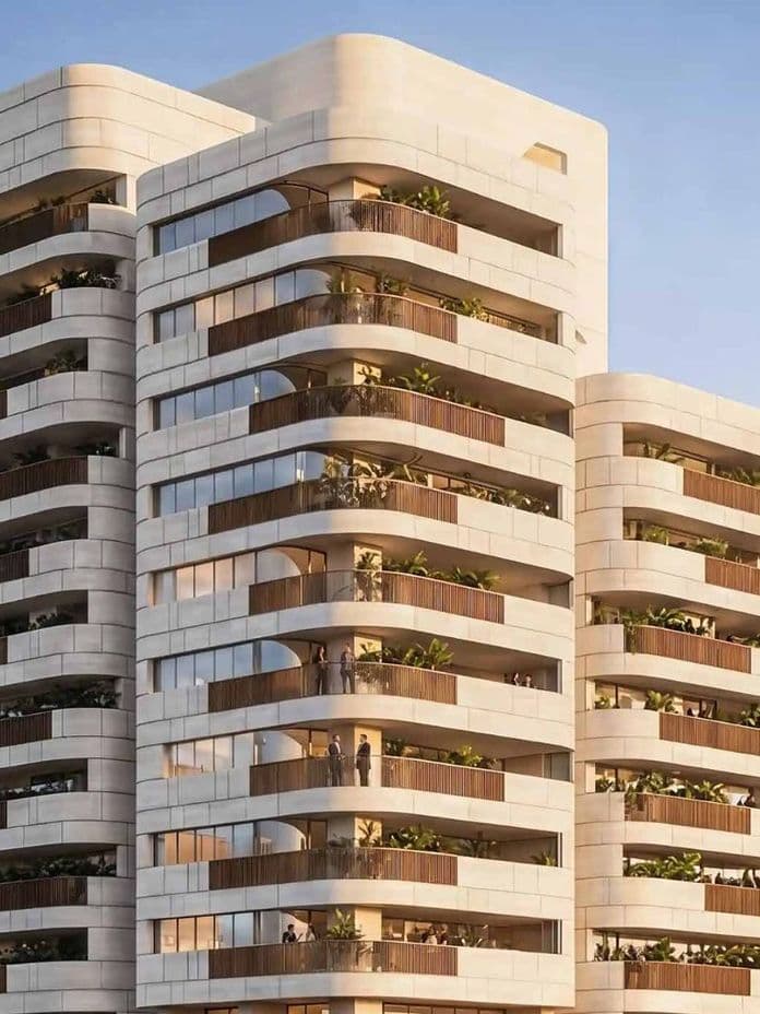 Modern multi-story building with staggered balconies featuring green plants, under a clear blue sky.