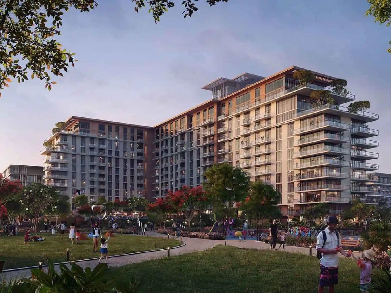 Modern apartment complex with balconies, surrounded by trees and a park. People are enjoying outdoor activities in the foreground.