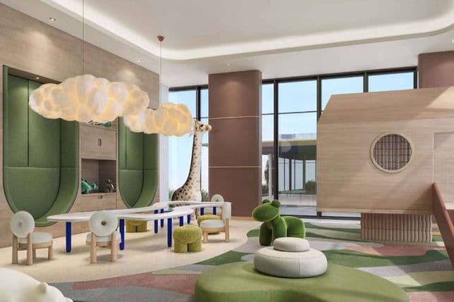 Bright children's playroom with glowing cloud pendant lights, plush green seating and stools, low table with chairs, wooden playhouse and tall giraffe toy.