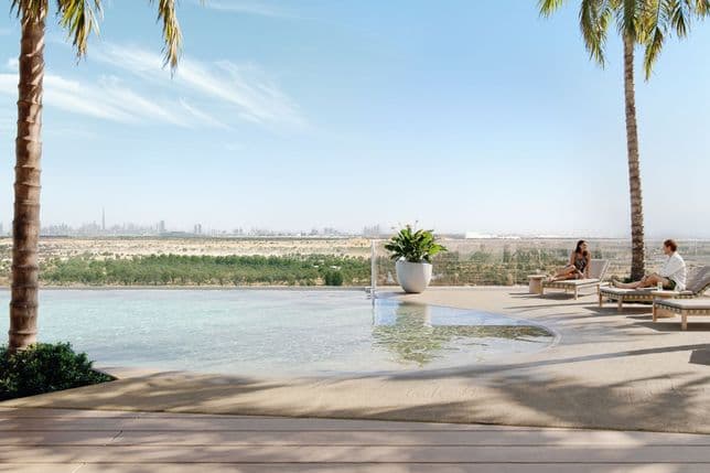 Infinity pool with city skyline view, palm trees, and two people relaxing on lounge chairs under a clear blue sky.