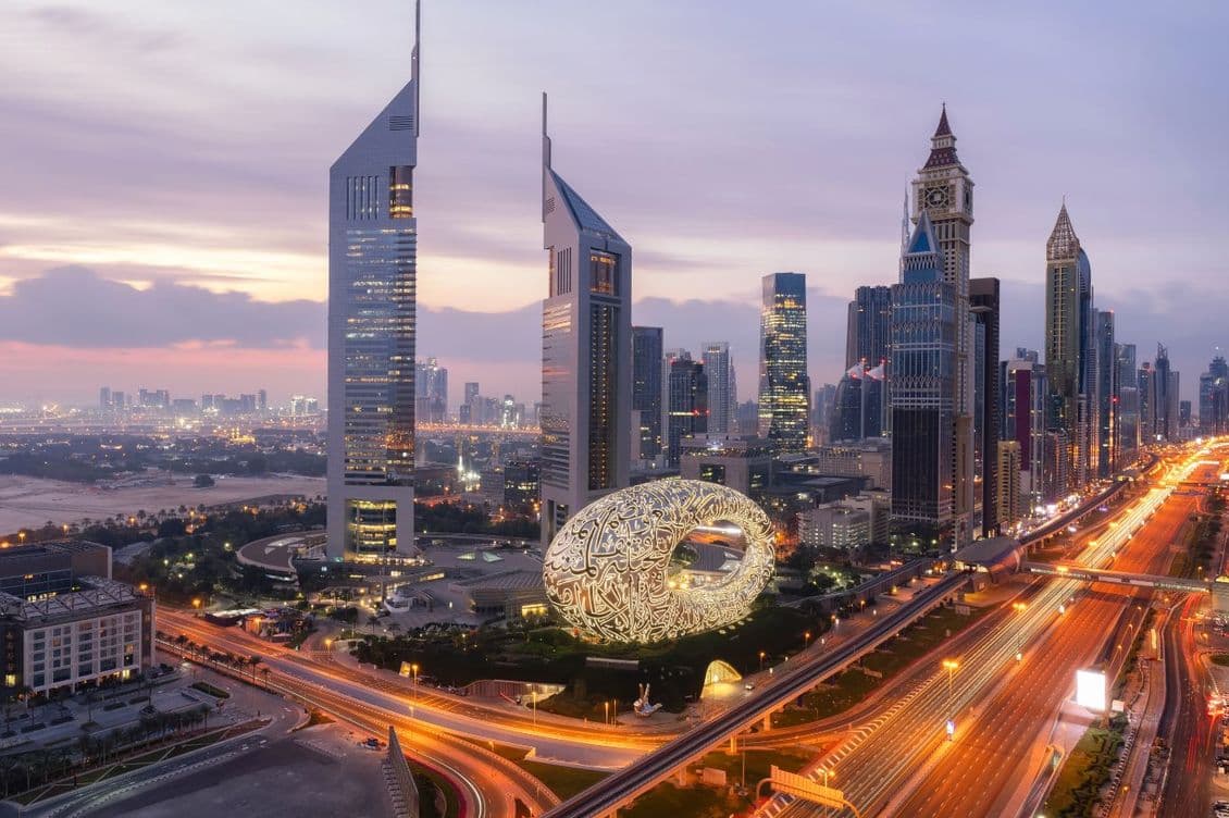 High-rise skyline of DIFC at sunset, with bright lights down Sheikh Zayed Road