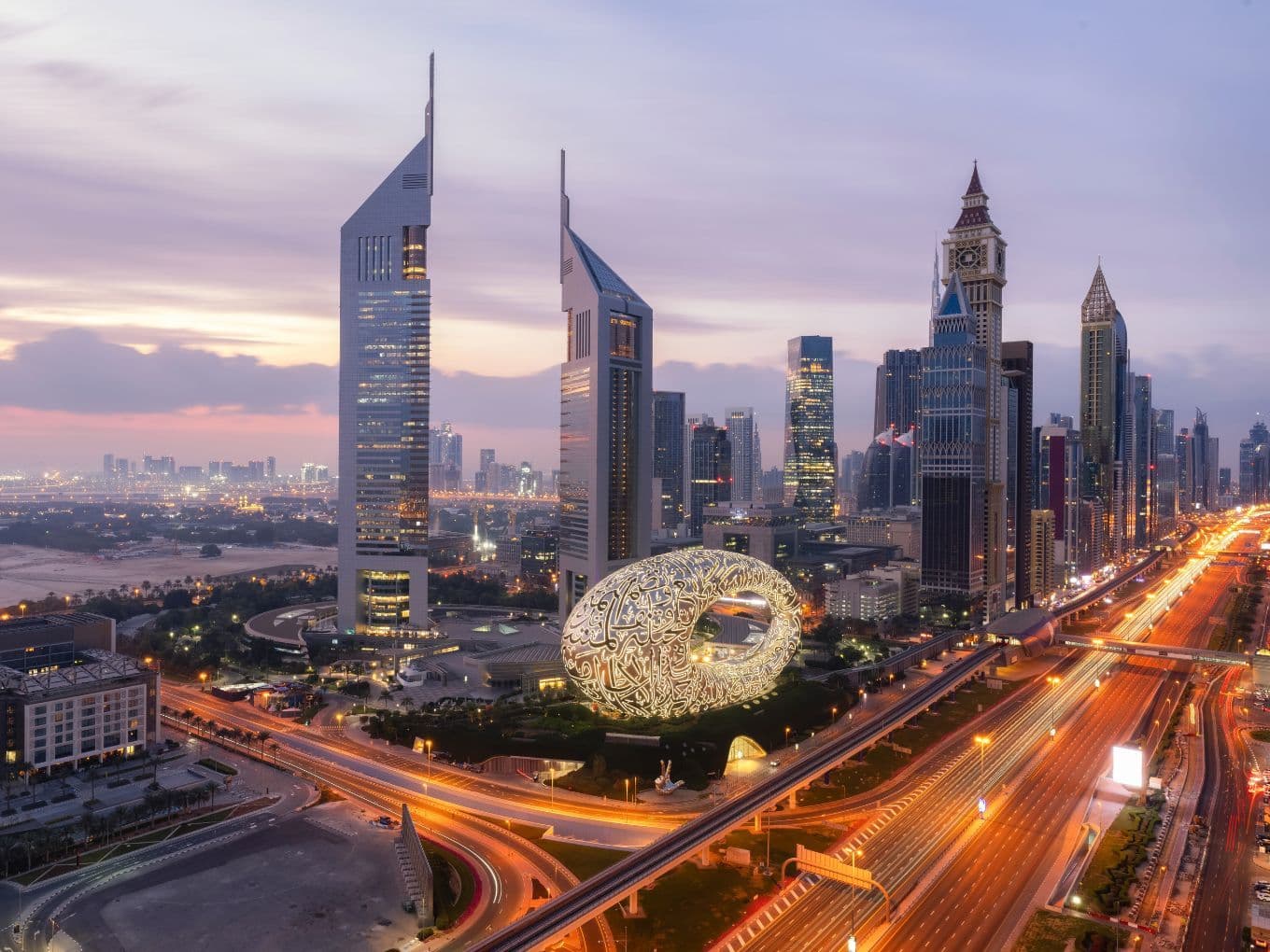 High-rise skyline of DIFC at sunset, with bright lights down Sheikh Zayed Road