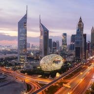 High-rise skyline of DIFC at sunset, with bright lights down Sheikh Zayed Road