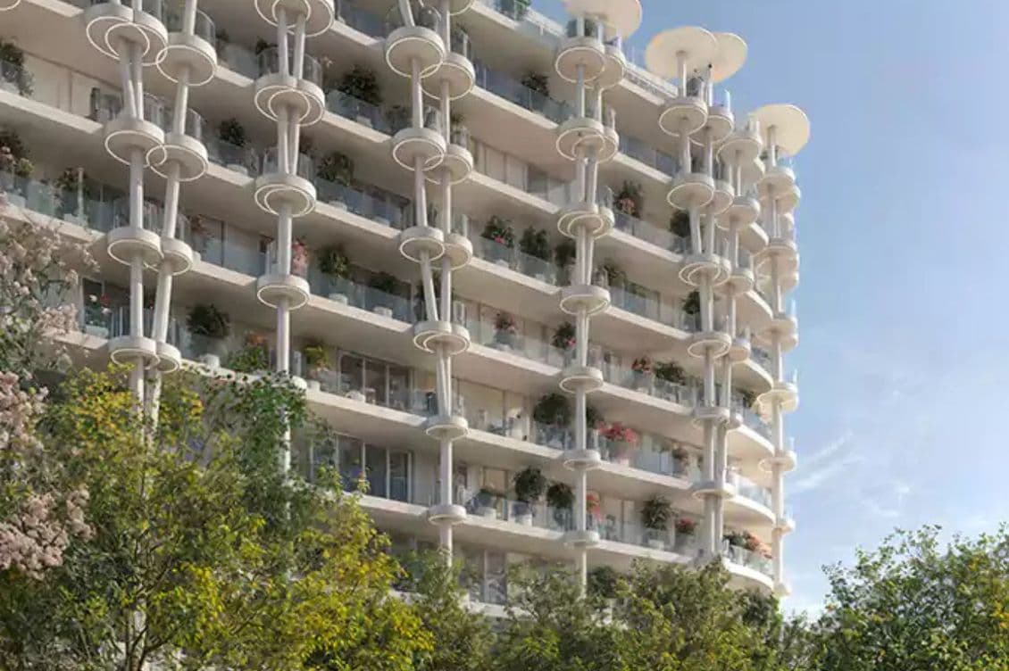 Moderne Außenansicht des Apartments mit markanten, ringförmig gestapelten Architekturdetails und begrünten Balkonen.