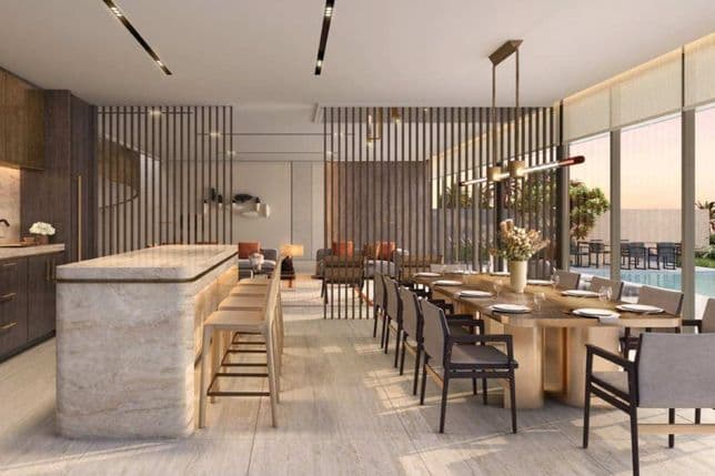 Modern dining and kitchen area with a marble island, long table set for dining, chic lighting, and a view of a pool outside.