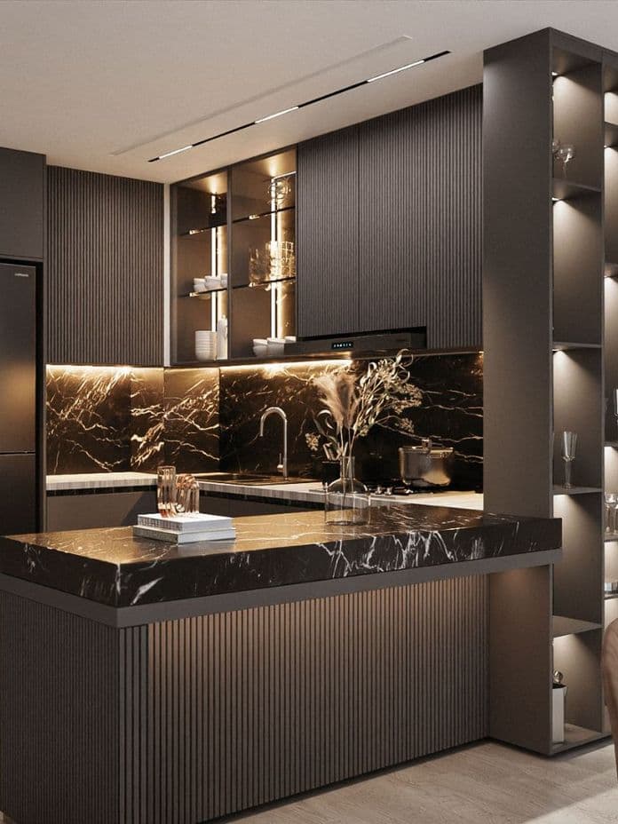 Modern kitchen with dark cabinets, marble countertops, and warm lighting. Includes a built-in fridge and decorative shelves with glassware.