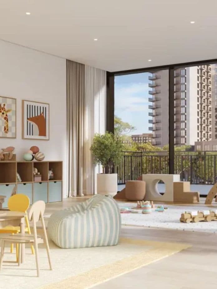Bright children's playroom with colorful chairs, wooden tables, toys, and a large window revealing a cityscape with tall buildings.