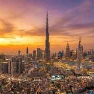 Aerial view of Downtown Dubai at sunset, featuring Burj Khalifa and vibrant orange and purple skies.