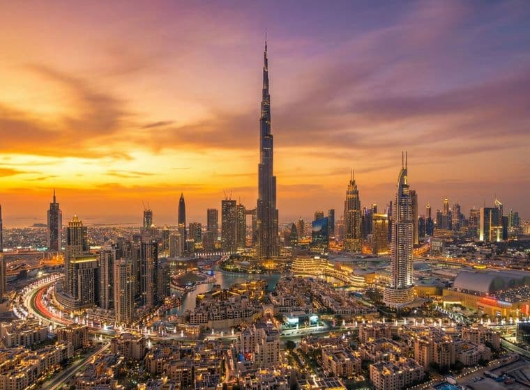 Aerial view of Downtown Dubai at sunset, featuring Burj Khalifa and vibrant orange and purple skies.