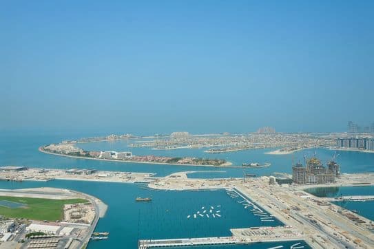 Elevated view from Cayan Tower in Dubai overlooking Palm Jumeirah, Atlantis The Palm, and surrounding turquoise waters with ongoing waterfront developments.