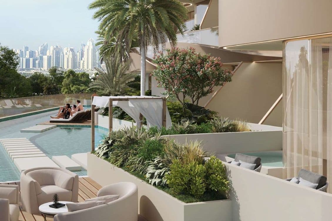 Luxurious poolside area with loungers, modern seating, lush greenery, and a city skyline view in the distance.