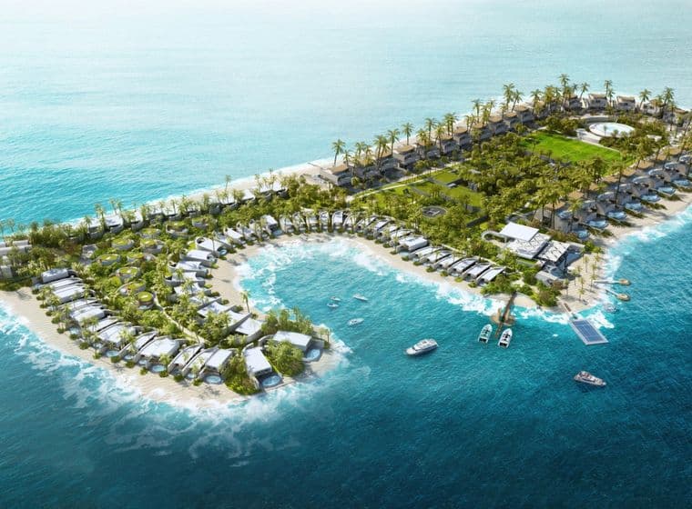 Aerial view of Zuhha Island resort with villas, palm trees, boats, and clear blue ocean waters.