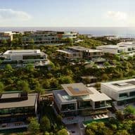 Luxurious modern villas on a lush hillside overlooking the ocean under a clear sky.