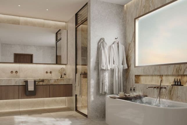 Modern luxurious bathroom with freestanding soaking tub, marble walls, backlit mirror, wooden vanity and two white robes.